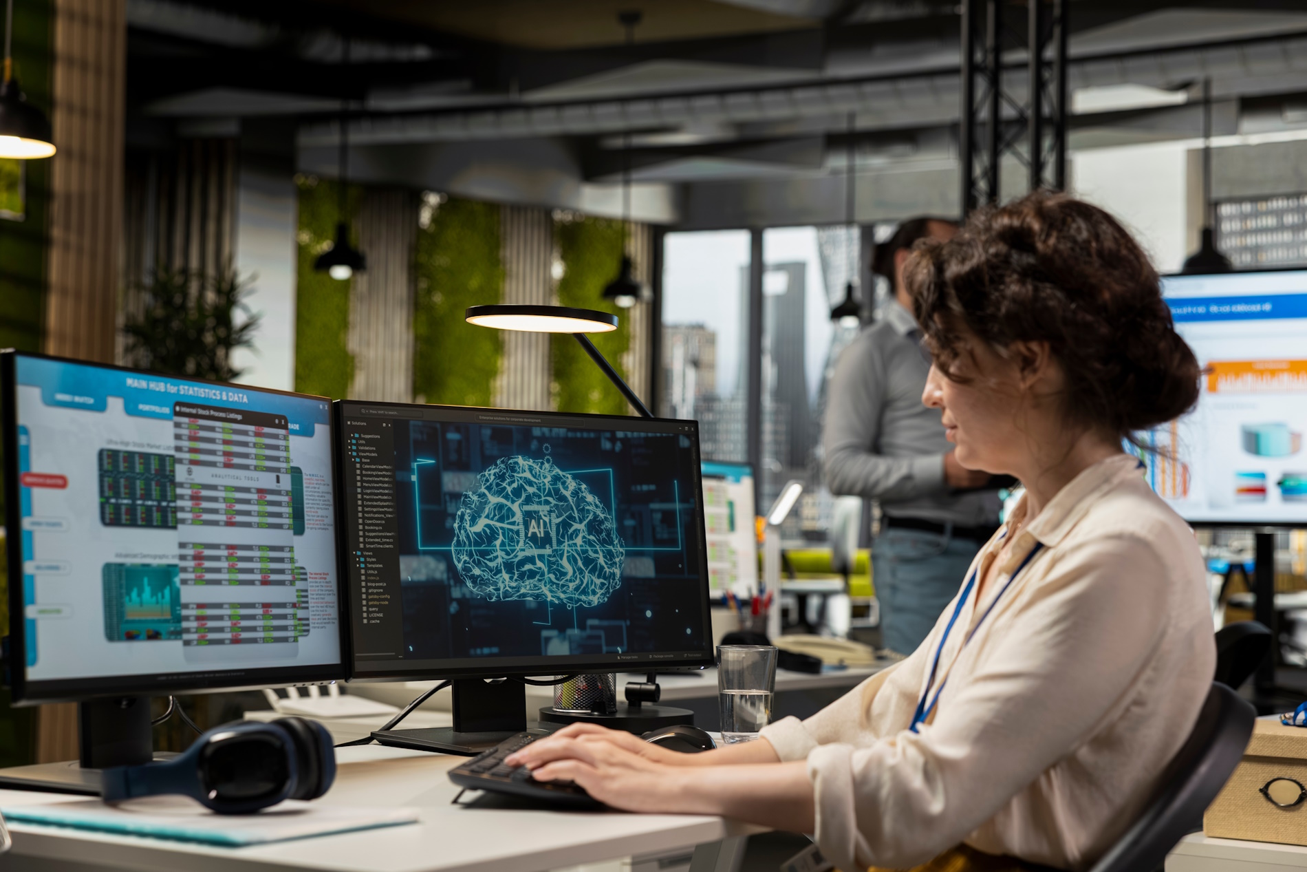 Eine Frau sitzt in einem modernen Büro an einem Schreibtisch mit mehreren Bildschirmen und arbeitet am Computer. Auf den Monitoren sind Datenübersichten, Diagramme und eine grafische Darstellung eines künstlichen Gehirns mit der Beschriftung ‚AI‘ zu sehen