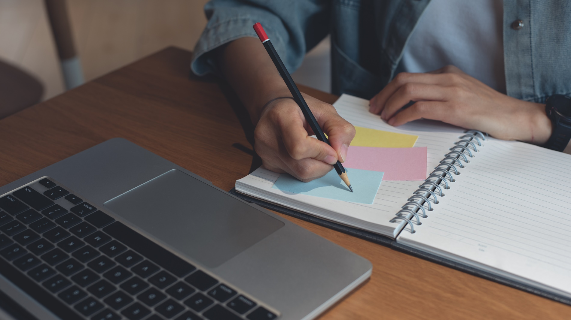 Auszubildender:in schreibt Notizen in ein Notizbuch.