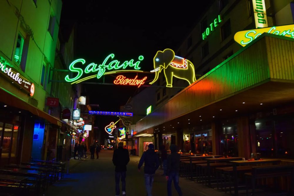 Reeperbahn in St. Pauli bei Nacht mit Leuchtreklame und Straßenbeleuchtung.